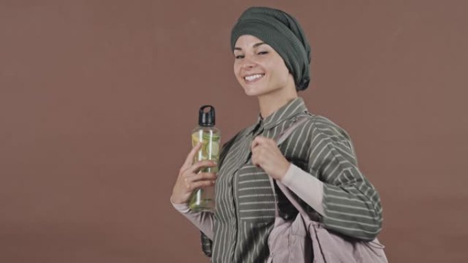 工作室里有运动包和水瓶的积极穆斯林妇女