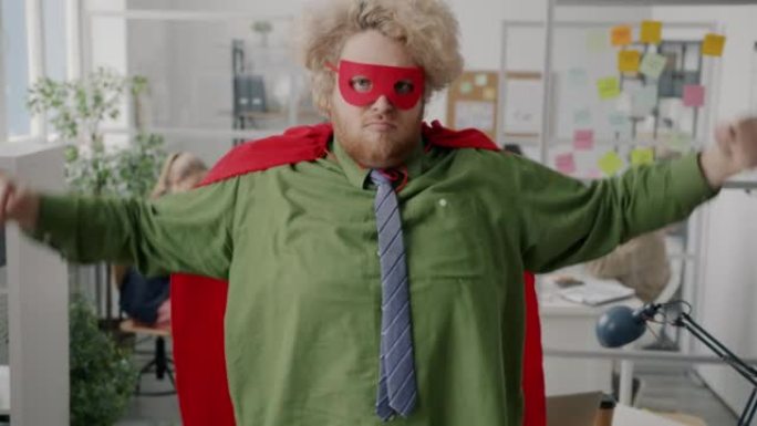 胖乎乎的上班族穿着超级英雄服装，在工作场所展示肌肉站立