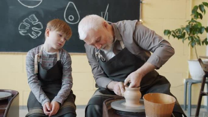 爱心祖父在投掷轮上制作陶瓷锅并与孙子交谈