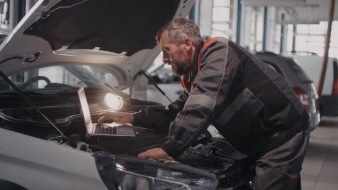 男性汽车机械师在诊断问题时使用笔记本电脑