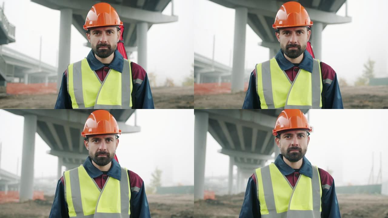 戴着安全帽和背心的测量员的肖像站在建筑工地，背景为测地线设备