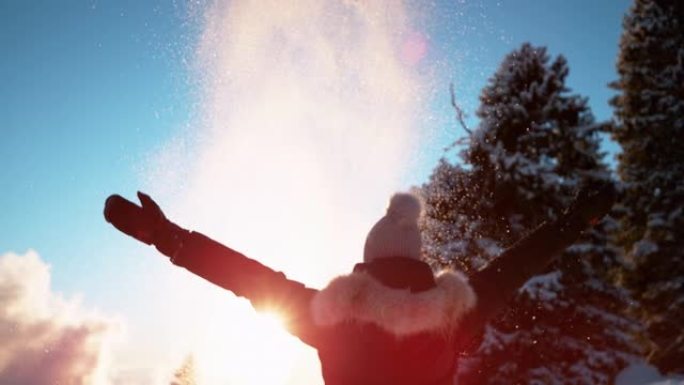 特写: 无法辨认的女人在日落时向空气中扔新鲜的粉末雪。