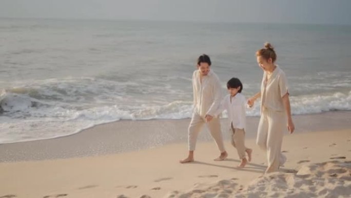 亚洲家庭牵着手在日落时沿着海滩散步