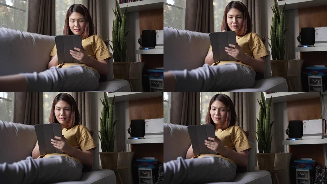 女人在家里的客厅沙发上使用数字平板电脑