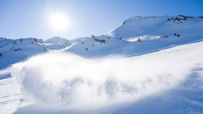 滑雪者在滑雪坡上雕刻，在背景中喷洒积雪，美丽的风景