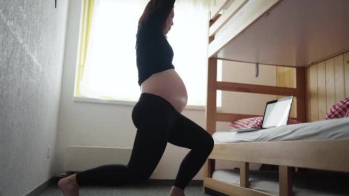 孕妇在家中用笔记本电脑在卧室锻炼