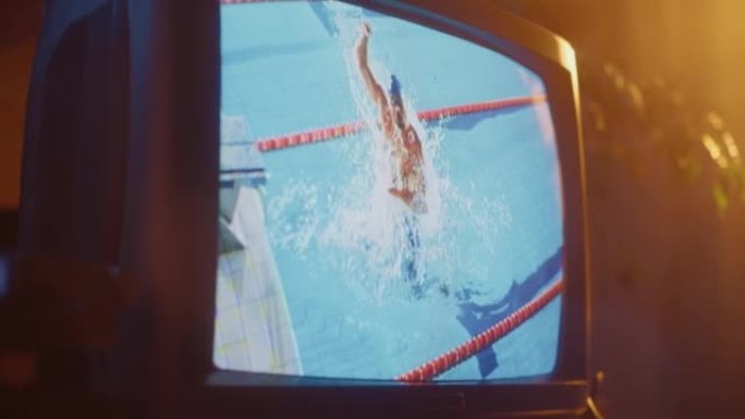 带有现场体育游泳比赛直播的复古电视机屏幕的特写镜头。在游泳池里表演健美操的运动员。怀旧年代的技术概念