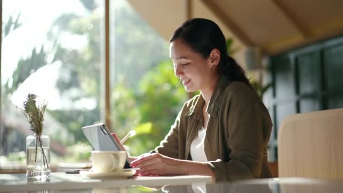 亚洲妇女在咖啡店使用笔记本电脑