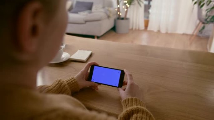 女士无法辨认的女人看着带有色度键蓝屏的智能手机