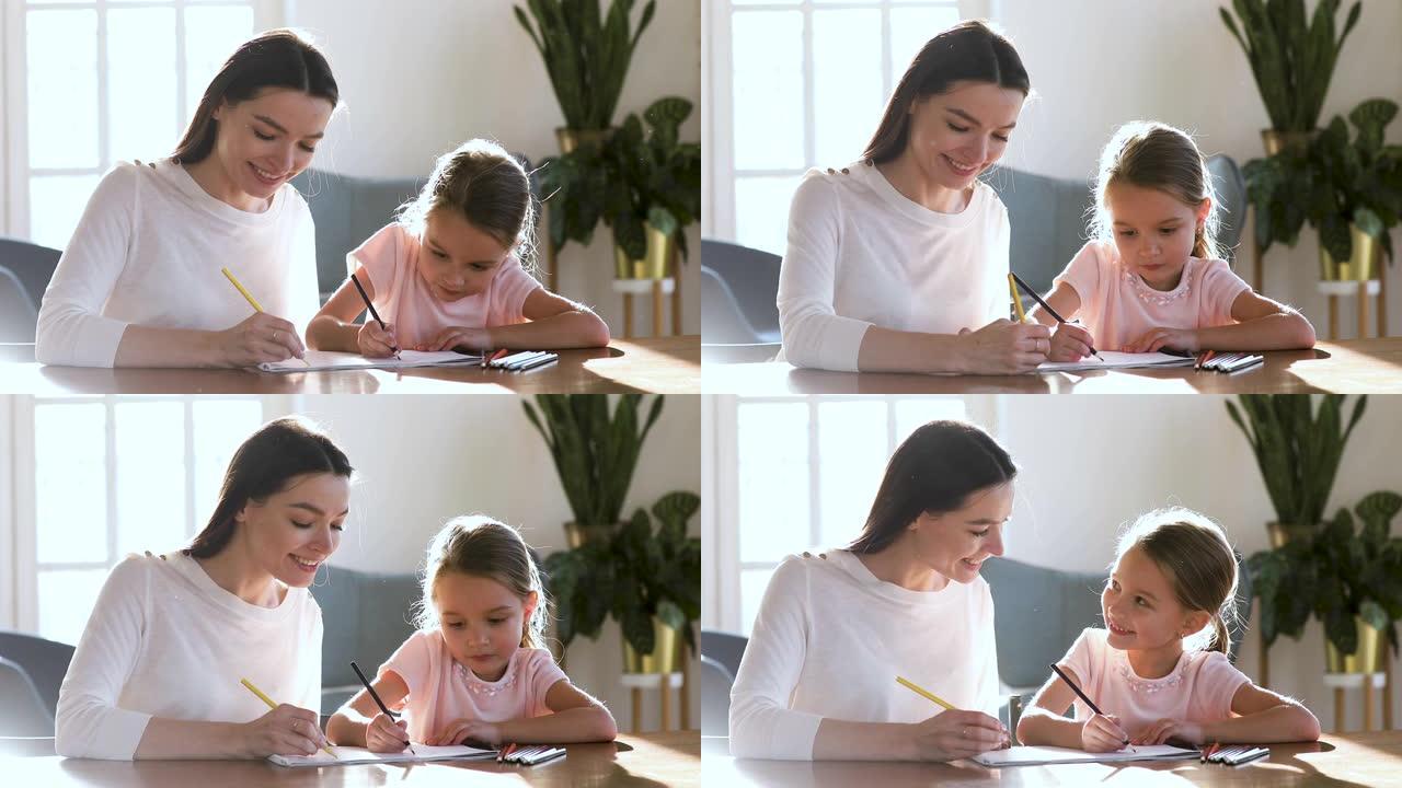 年轻的保姆和女儿在纸质相册里画画。