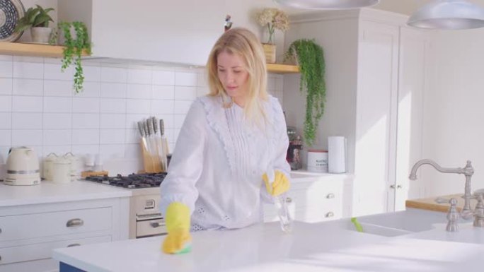 女人在家做家务戴着橡胶手套用喷雾和布清洁厨房柜台
