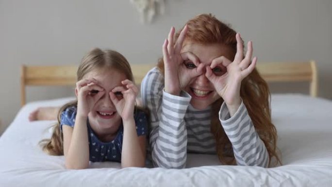 女儿，母亲通过手指看着相机使眼镜成形