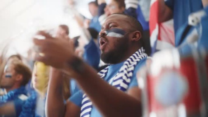 体育馆大事件: 英俊的黑人欢呼。一群脸上涂着彩绘的球迷欢呼，为他们的蓝色足球队获胜而呐喊。人们庆祝进