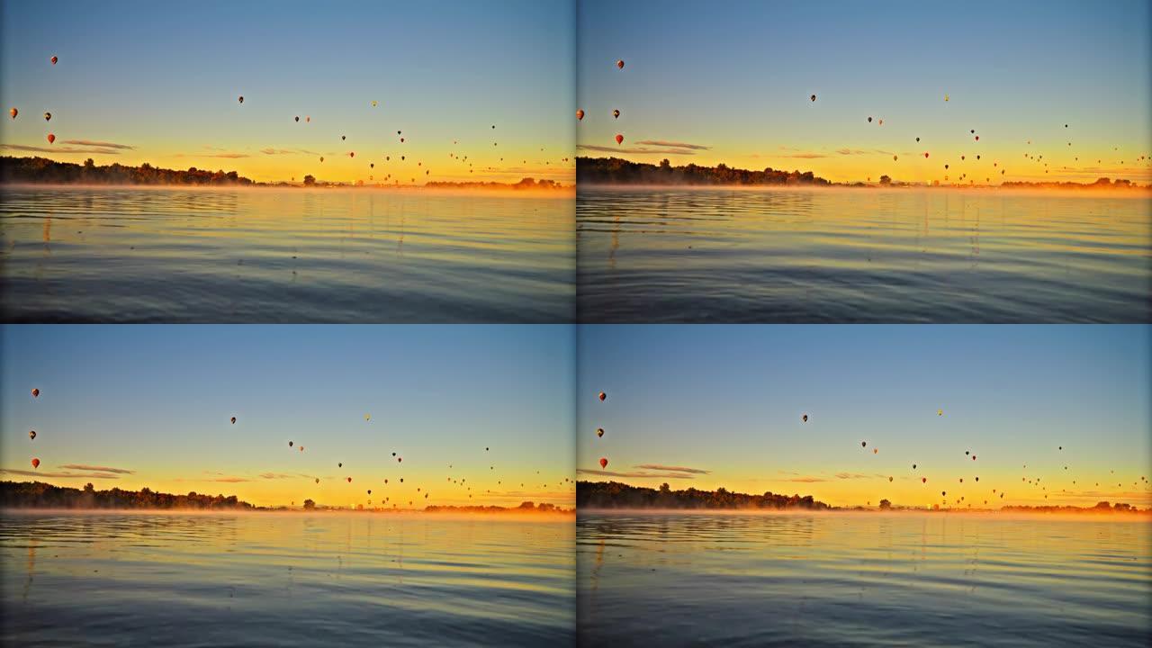 水面景观热气球在田园诗般的日出天空中飞行