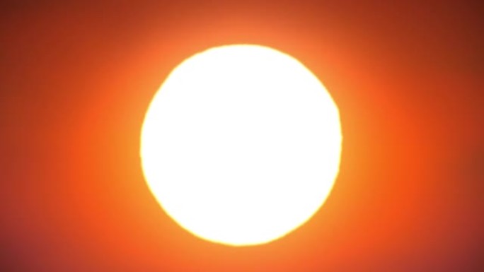 美丽清晰的大日出 (日落) 特写循环动画。巨大的静态橙色炎热的太阳在温暖的空气扭曲地平线上无缝。美丽