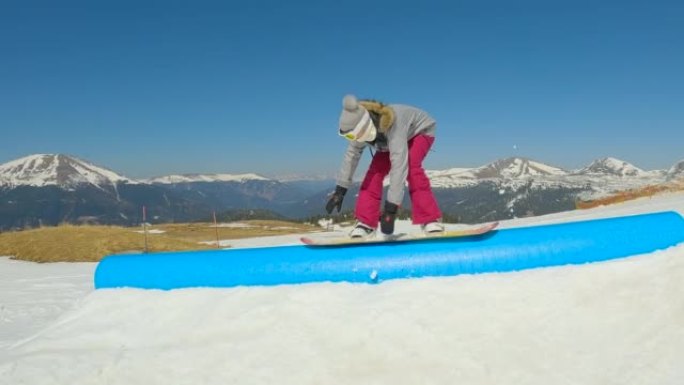 慢动作: 女孩滑雪者在滑轨时失去平衡后摔倒