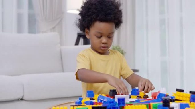 肖像2-3岁的小男孩的非洲种族在家上学时玩五颜六色的玩具积木呆在家里，以防止家庭生活中冠状病毒或Co