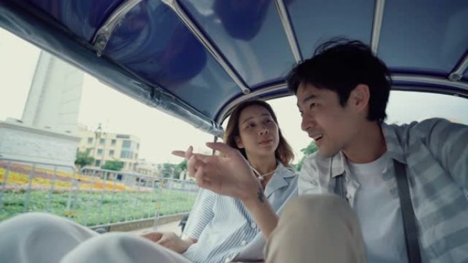 年轻英俊的男人和他的女朋友骑着传统的嘟嘟车夫妇在蜜月期间旅行泰国