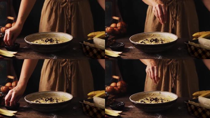 女人在搅拌碗中的香蕉面包面糊中加入choco片的特写镜头