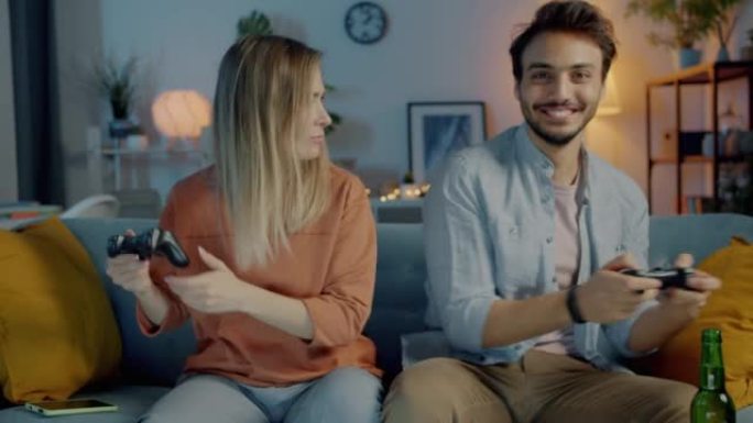 快乐的男人和女人在晚上在公寓里玩电子游戏的肖像