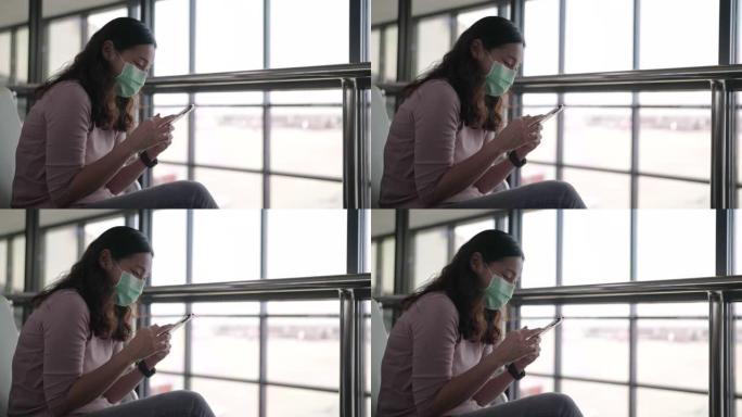 亚洲女游客在机场使用智能手机戴防护口罩