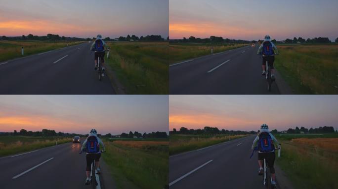 黄昏时在田野之间的主要道路上骑自行车