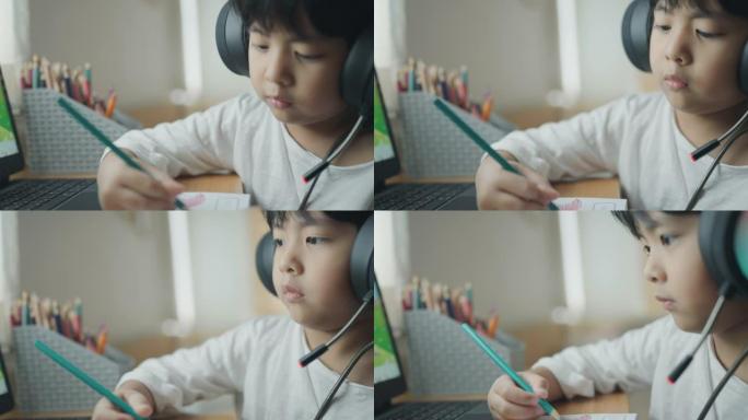 一个戴着耳机的男孩在家上网学习