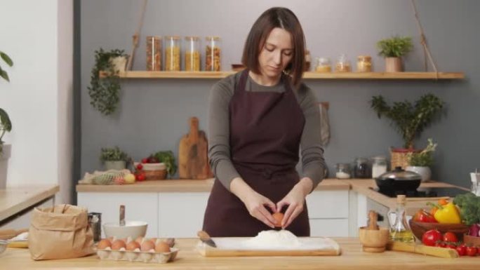 女人在家做饭时向面粉中添加鸡蛋