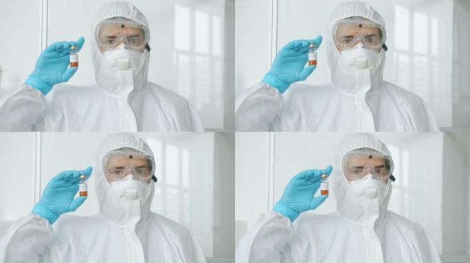 穿着防护服的男医生的肖像站在新型冠状病毒肺炎隔离单位拿着疫苗看着相机