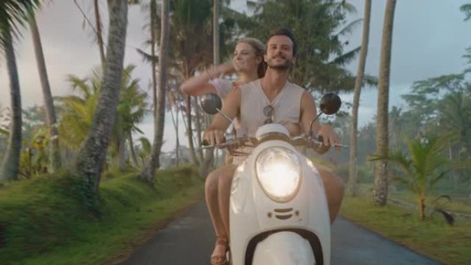 快乐的夫妇骑踏板车在热带岛屿上快乐的女人举起手臂庆祝享受与男朋友骑摩托车在晨雾中的浪漫冒险