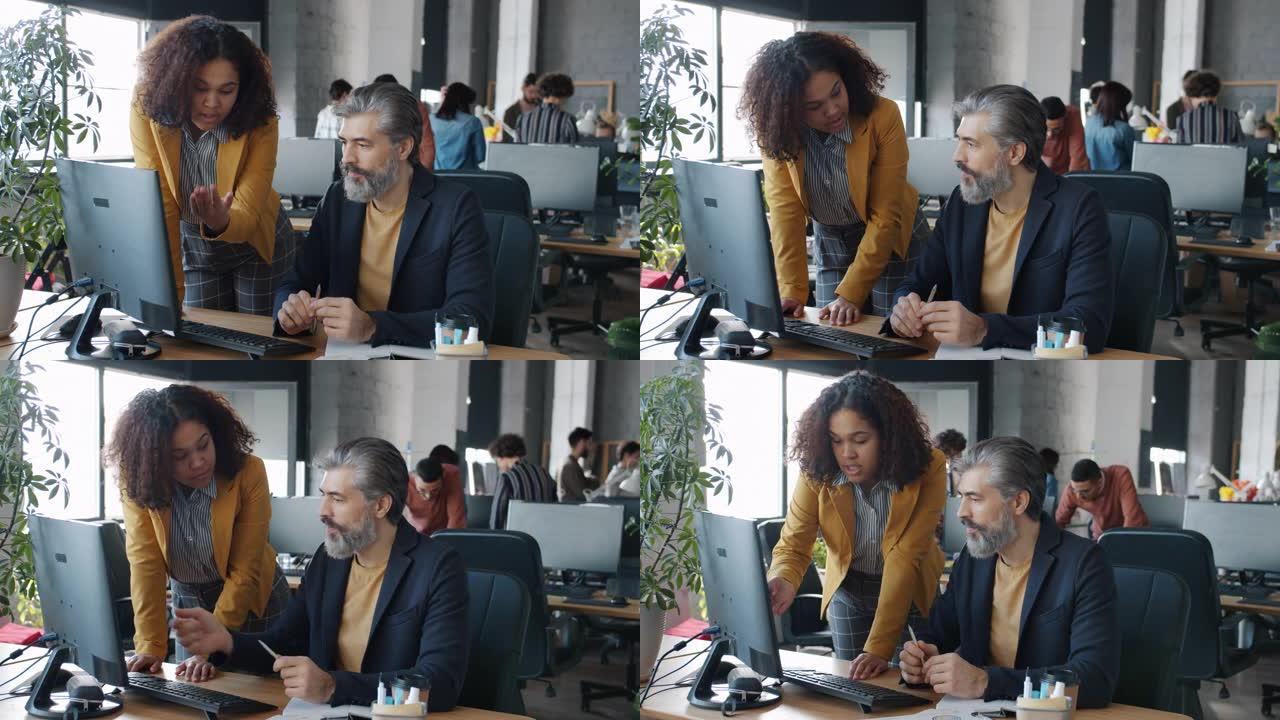 同事男女在办公室里看着电脑屏幕讨论工作