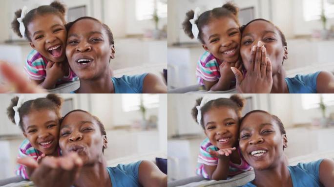 快乐的非洲裔美国母亲和女儿在家里自拍，给空气亲吻
