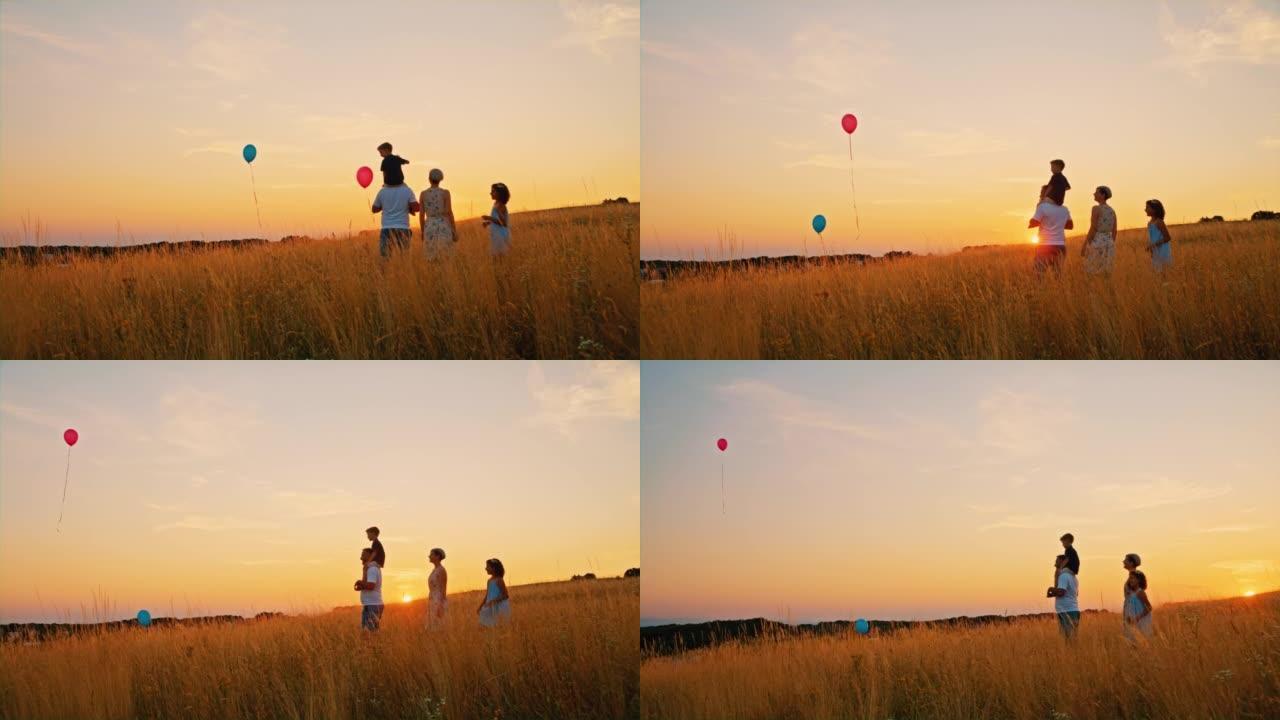 SLO MO家族在日落时分释放气球飞向草地中央的空中