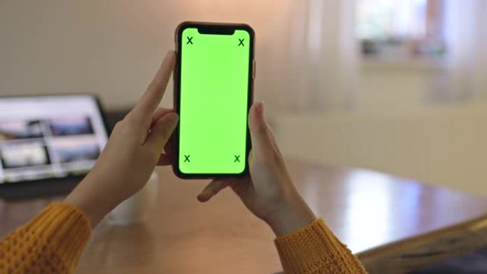 女士无法辨认的女人在家中拿着色度键绿屏智能手机