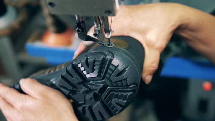 工厂工人正在机械缝制靴子。鞋类生产设施。