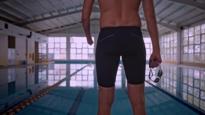 自适应截肢游泳者站在室内游泳池外手持护目镜