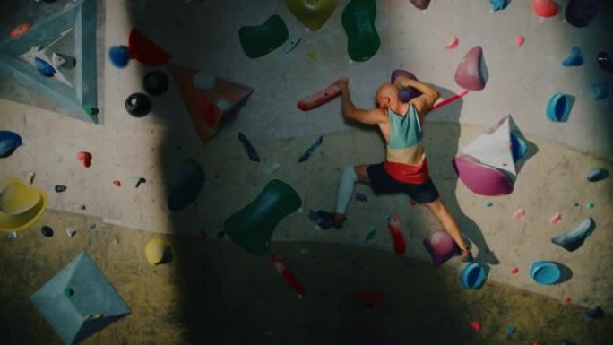 经验丰富的攀岩者在健身房的抱石墙上练习单人攀岩。男子在室内健身设施锻炼，进行极限运动以进行健康的生活