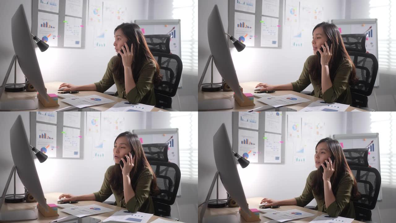 亚洲女商人在电脑上工作，在办公室接电话