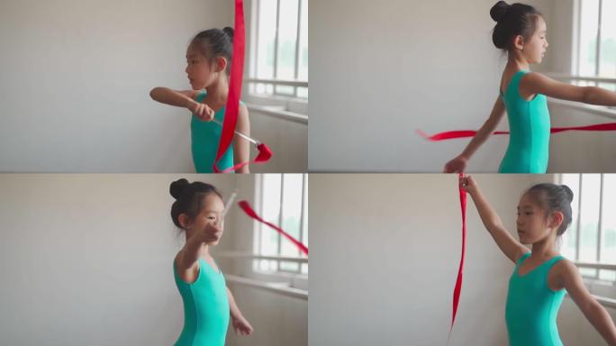 慢动作亚洲中国年轻女孩在体操学校用彩带练习艺术体操。芭蕾舞学校。