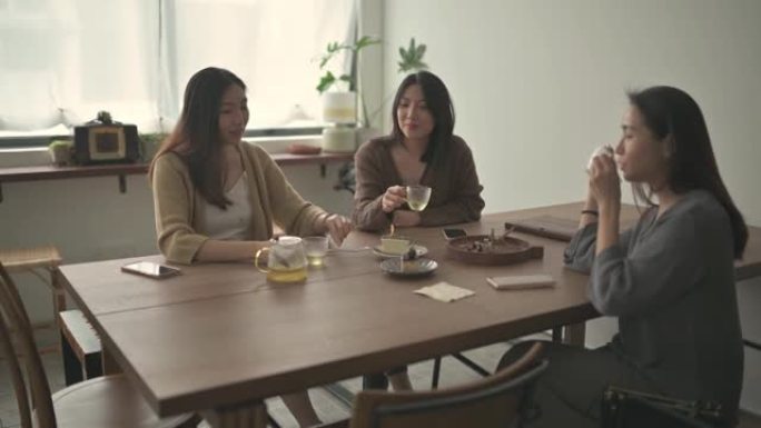 3位享受下午茶的中国女性朋友在周末休闲时间与彼此在咖啡馆分享甜点