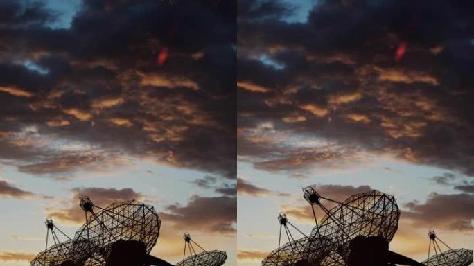 许多射电望远镜指向夕阳下的天空，上面有彩色的云彩。天文研究概念