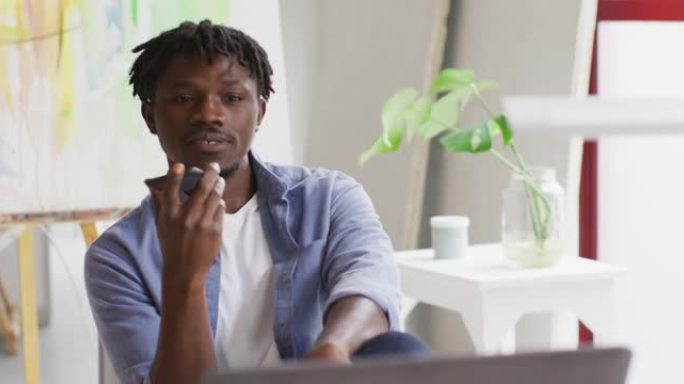 非裔美国男艺术家在art studio的智能手机上聊天