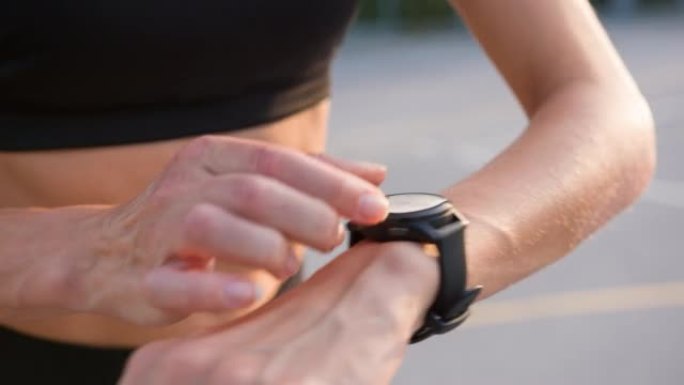 女跑步者在智能手表上检查她的脉搏轨迹并调整另一圈跑步