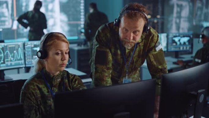 军事监视人员在中央办公室的计算机屏幕旁交谈，以进行网络操作，控制和监视，以管理国家安全，技术和军队通
