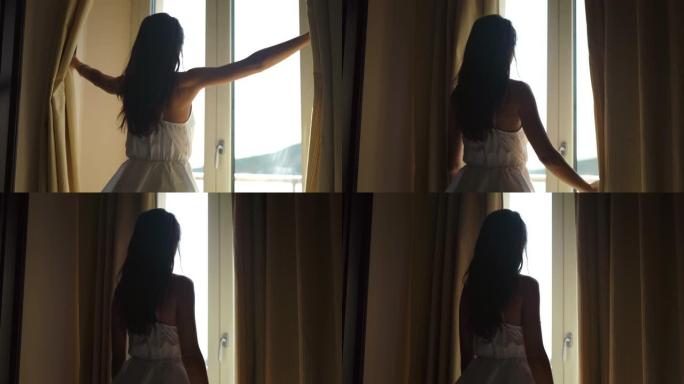 一个穿着白色连衣裙的年轻晒黑的赤脚女人的真实照片是在暑假期间的一个早晨醒来的窗户，并在旅馆房间里打开