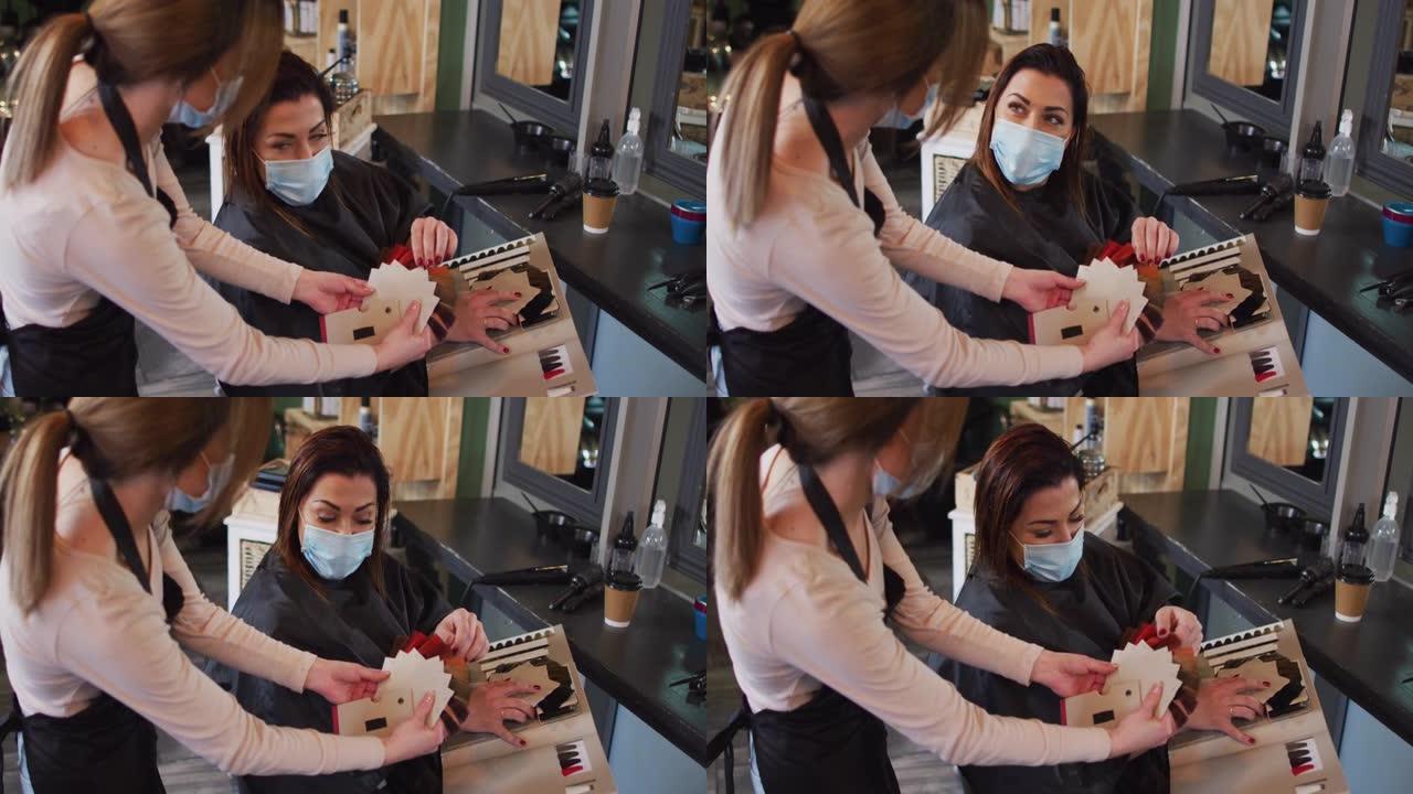 女性美发师戴口罩向女性顾客展示头发颜色样本图