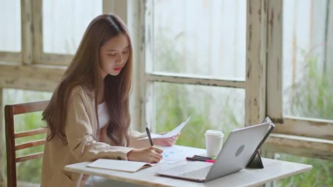 亚洲女性自由职业者在办公空间咖啡馆使用笔记本电脑远程工作。