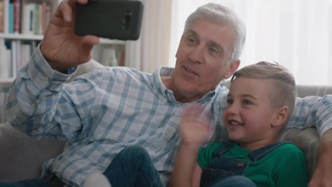 祖父和孩子使用智能手机进行视频聊天小男孩与家人共享假期周末爷爷在家里与孙子一起享受移动技术聊天