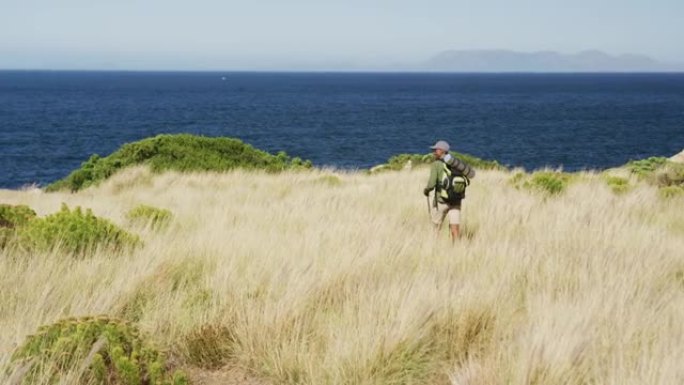 非裔美国人在海岸边的乡村徒步旅行，用登山杖徒步旅行