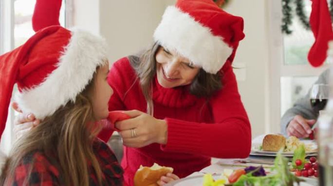 快乐的高加索母亲在圣诞节餐桌上擦女儿的嘴